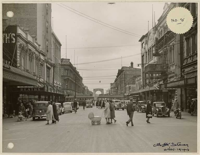 Busy Cashel Street in Christchurch in 1946 with the Bridge of Remembrance in the background and Beaths Department Store on the left