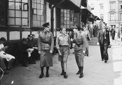 Two female police officers escorting a detained juvenile to a police holding cell in front of the Temporary Main Station building in Warsaw
