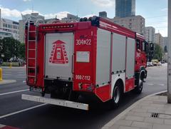Red MAN fire engine with ladder and emergency equipment driving in Warsaw, Poland