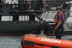 Crewman mans weapon on bow of 25-foot Coast Guard response boat during USS Constitution turn around in Boston harbor
