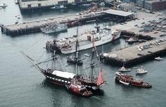 Aerial view of the 44-gun sail frigate USS Constitution in Boston Harbor assisted by a fire tug during annual turnaround cruise after a 21-gun salute