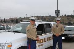 Two military policemen standing in front of a Marine Corps Recruit Depot San Diego K-9 vehicle before a funeral procession