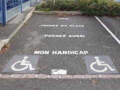 Disabled parking space sign at Colmar main train station with message asking to respect the space and disability