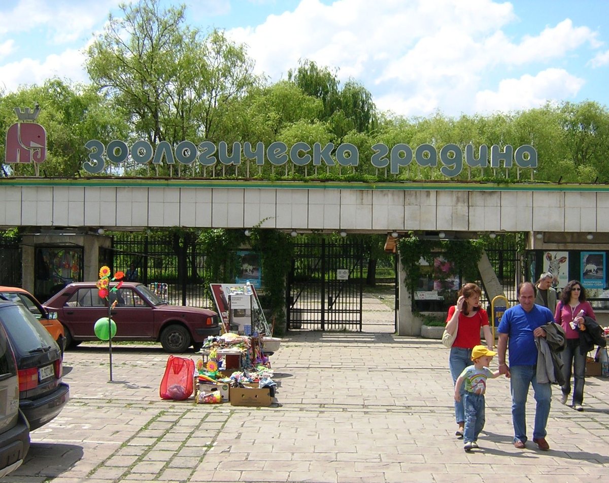 Entrance gate of Sofia Zoo with sign and surrounding greenery