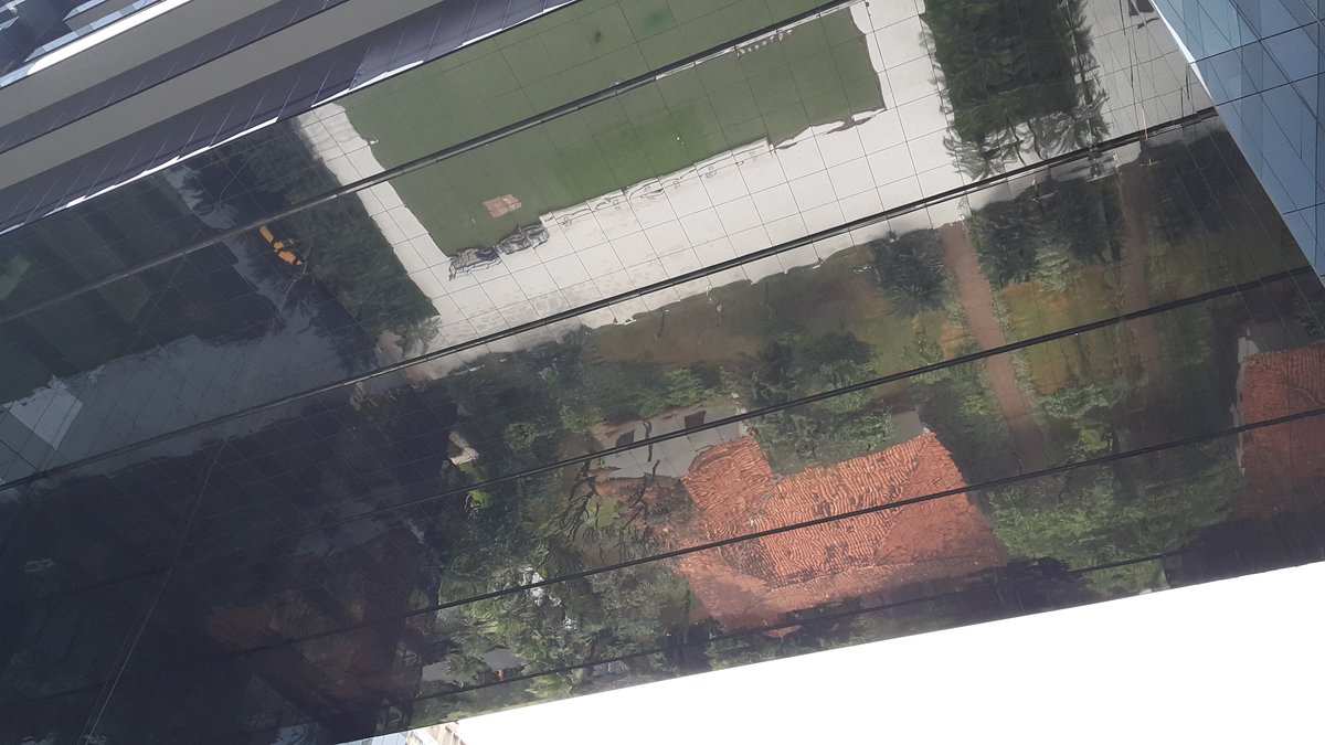 Reflection of the historic Bandeirista House of Itaim in the windows of the Pátio Victor Malzoni Building in São Paulo
