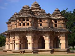 Ruins of ancient stone structures and a water tank in Hampi under clear blue sky