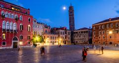 Santo Stefano church in Venice illuminated during blue hour with calm canal in foreground